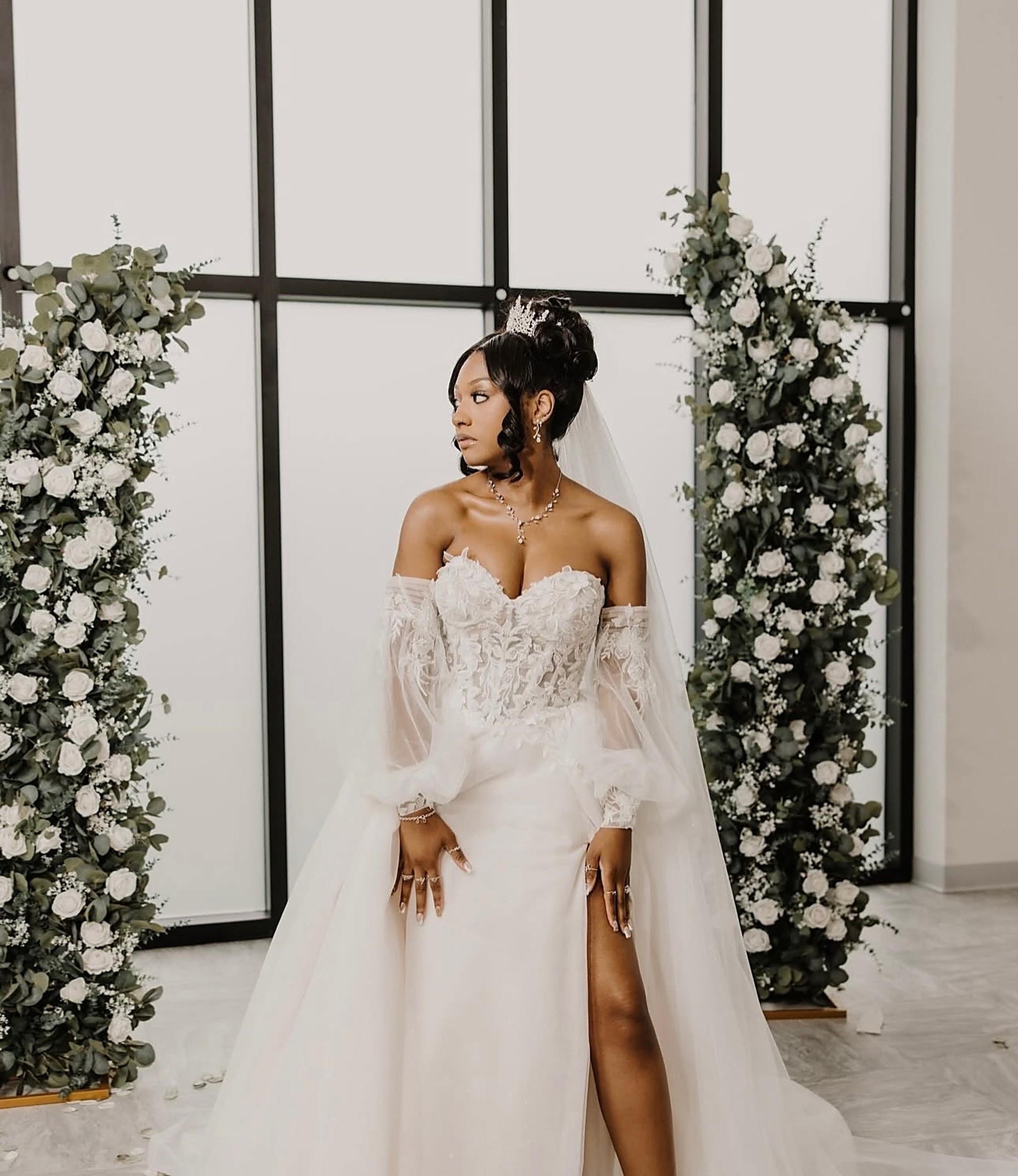 Bridal lace install with tiara and veil before a white floral arch